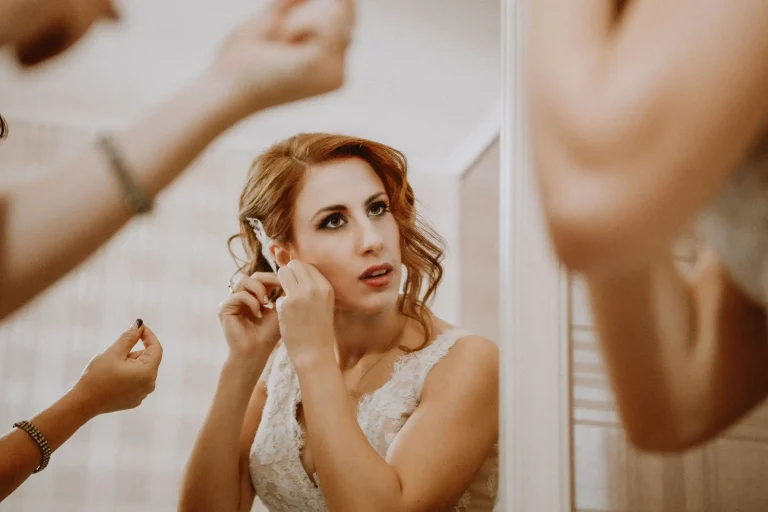 Elena putting on an earring in front of a mirror during bridal preparations