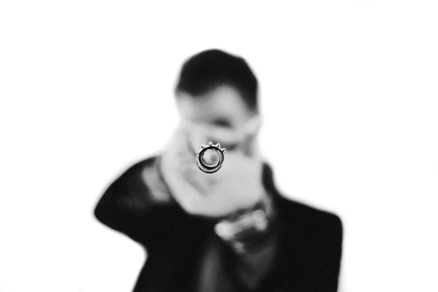 Black-and-white studio portrait of Despoina holding her engagement ring towards the camera