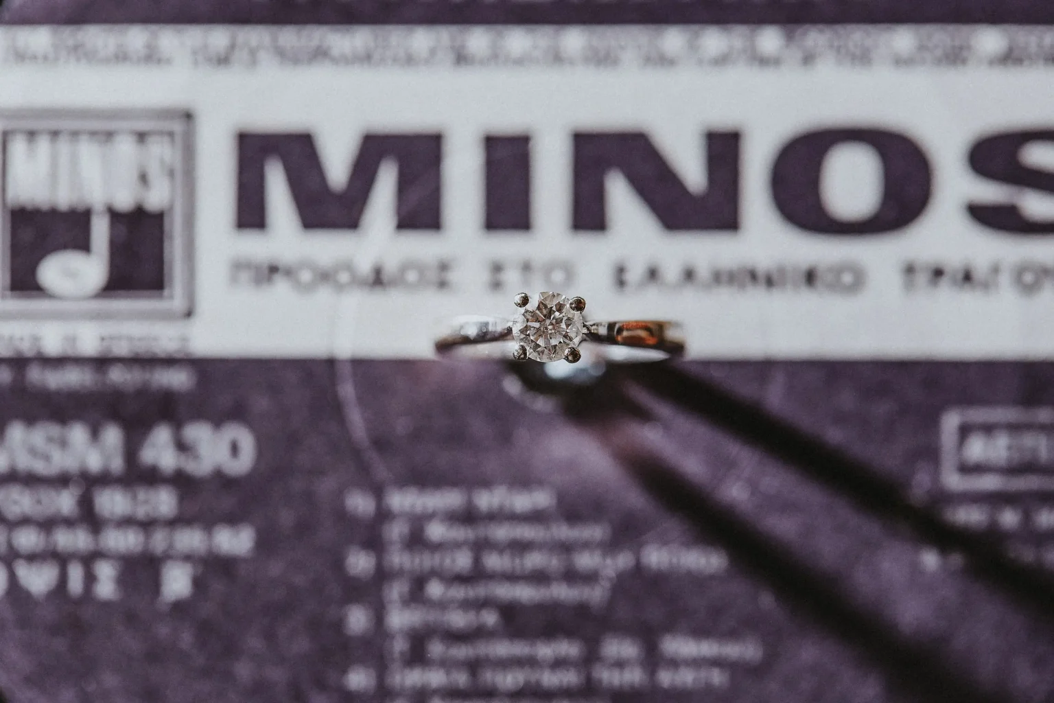 Diamond engagement ring resting on a vintage Greek record sleeve