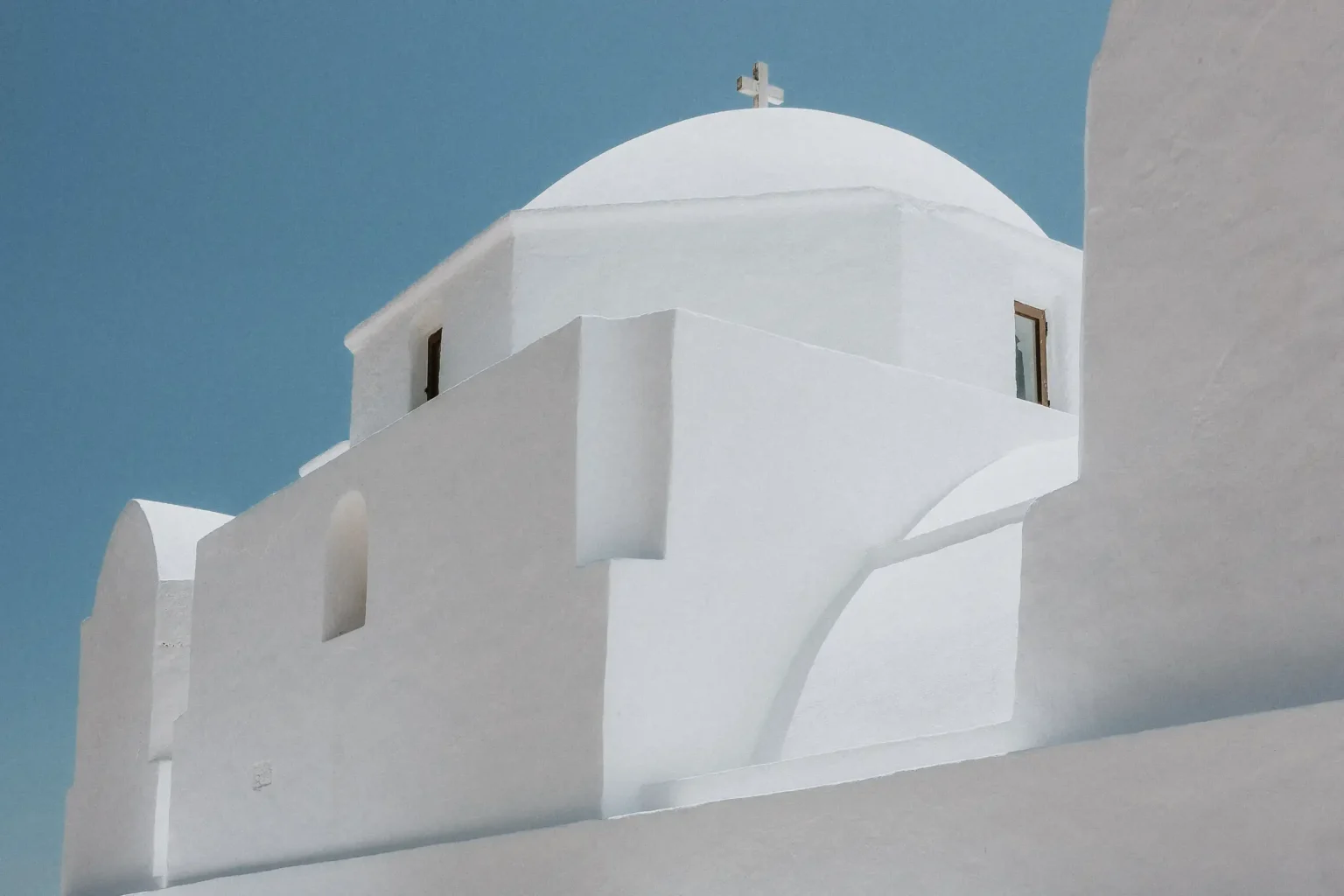 Whitewashed dome and curved walls of the Church of Panagia in Folegandros beneath a blue sky