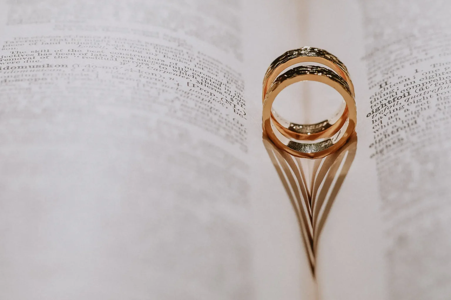 Carly and George’s gold wedding rings on an open book, casting heart-shaped shadows