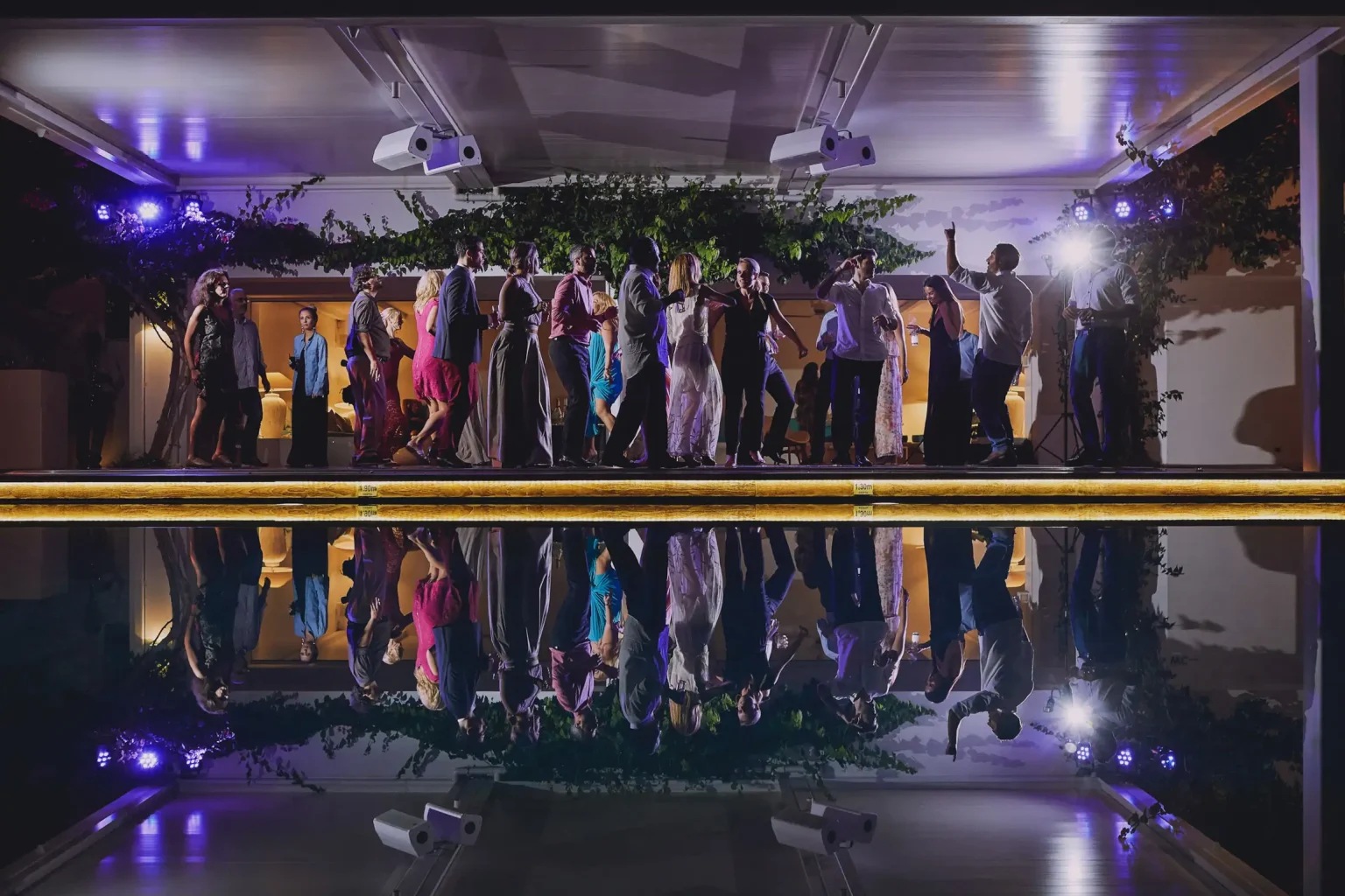 Wedding guests dancing beside the pool at Ktima 48, reflected in the water at night