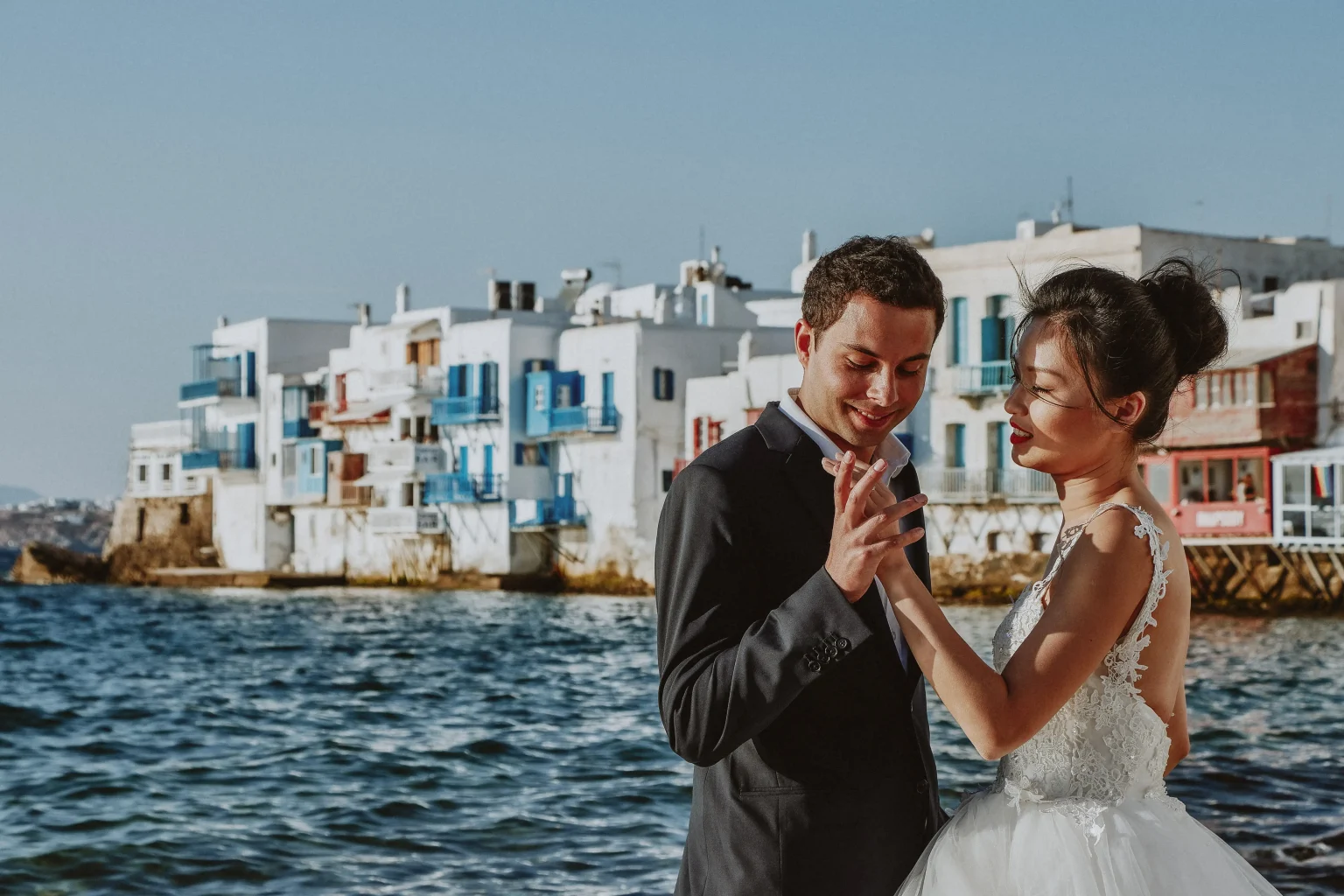 Sandra and Romain holding hands by the sea in Little Venice, Mykonos