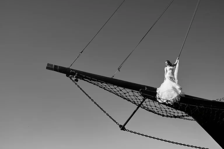 portrait of bride standing on the bow beam of old wooden scooner