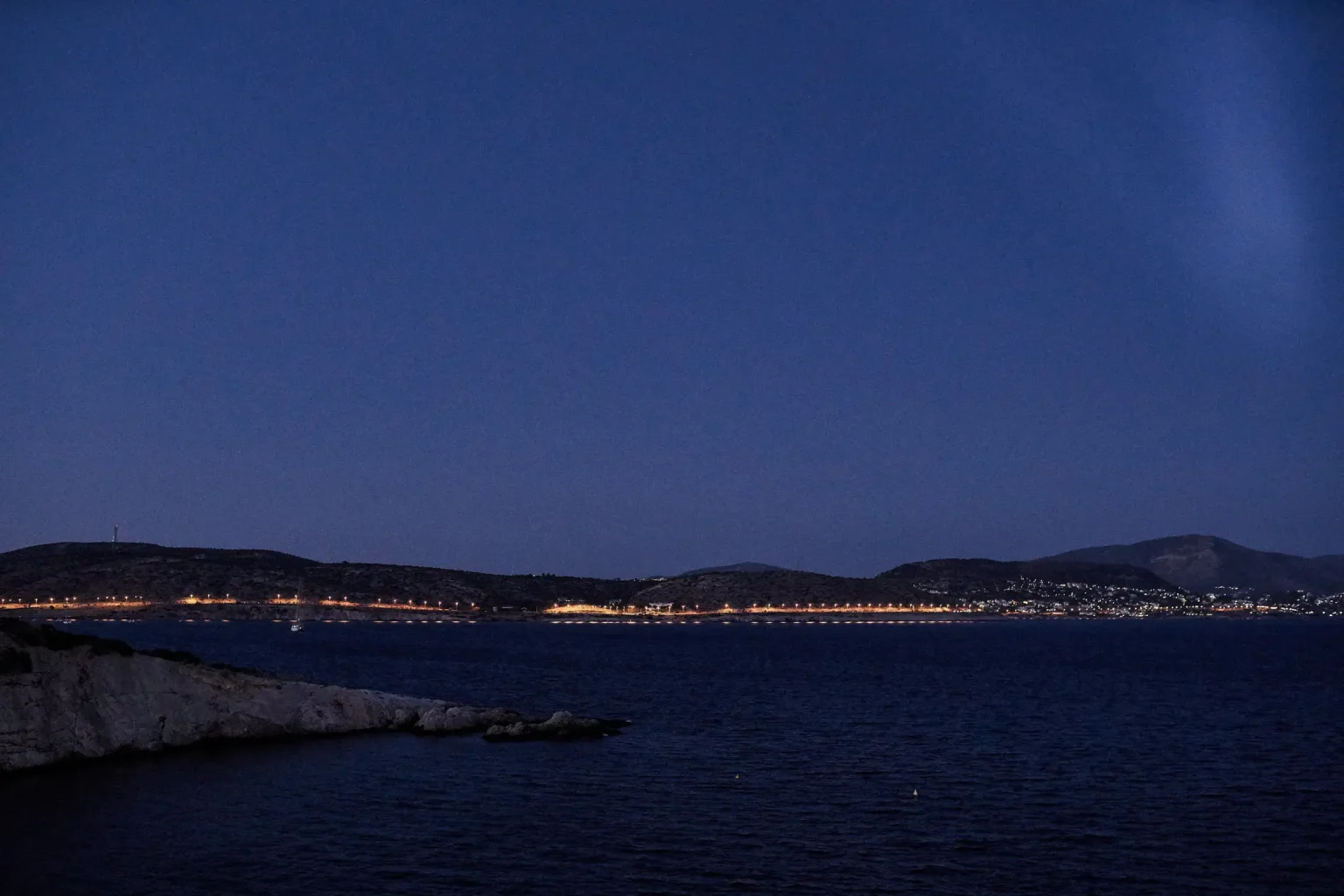 Coastal lights across the sea at dusk, viewed from Island Gallery on the Athens Riviera.