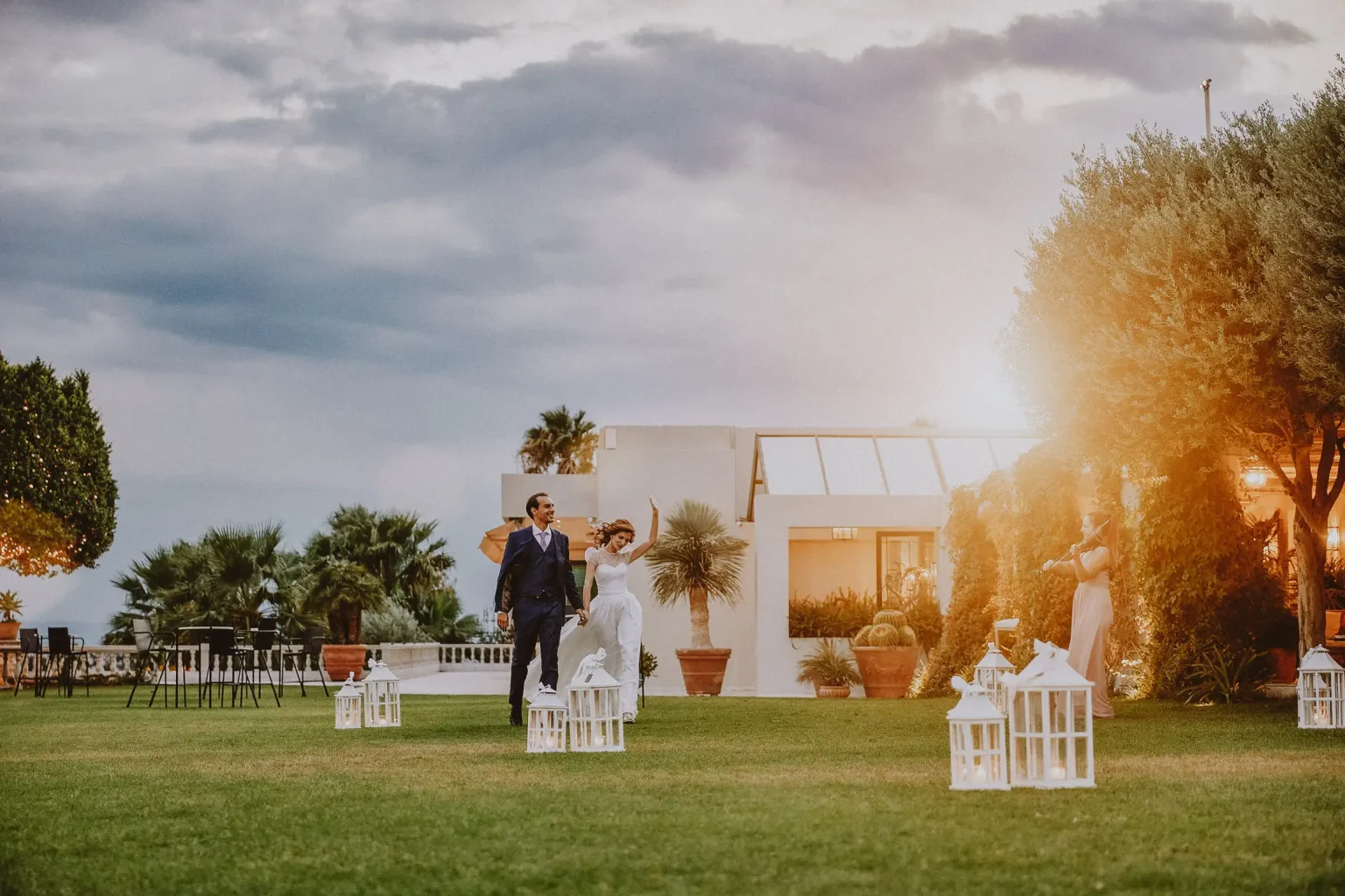 Elena and Christos walking hand in hand into their reception at Golf Privé, with Elena raising her arm