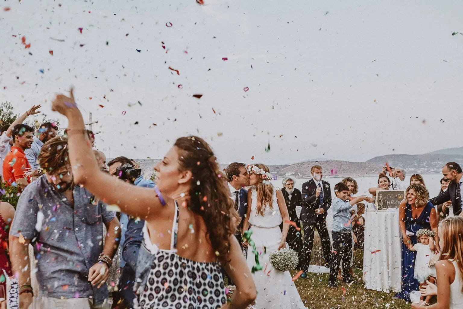 Maite and Alex kissing as wedding guests shower them with colourful confetti